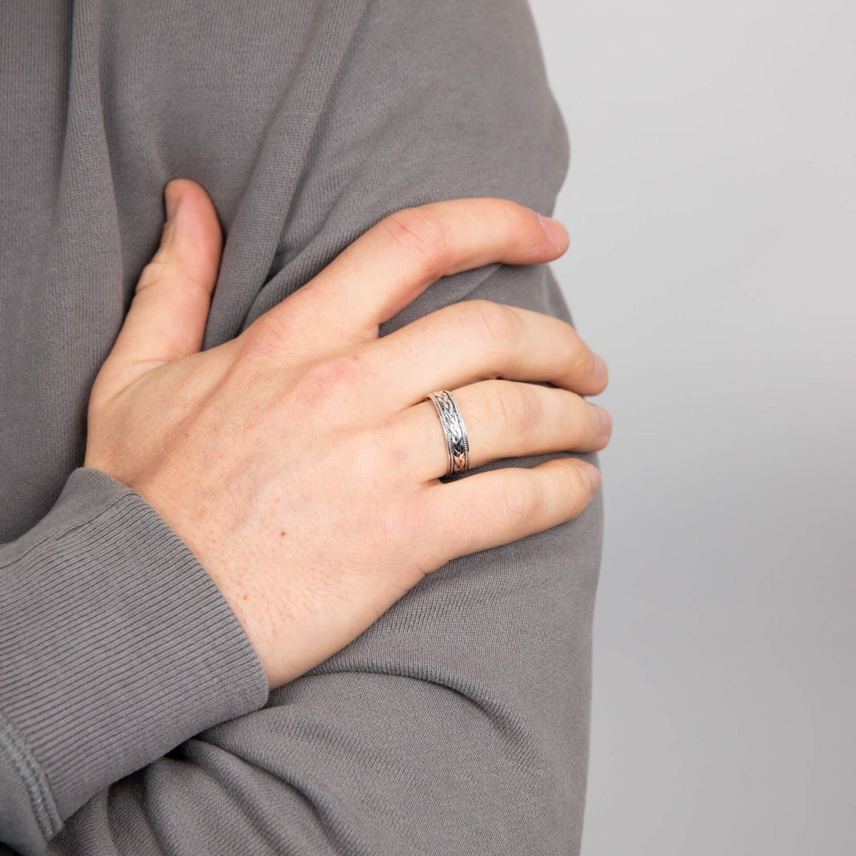 Anello fascia celtica semplice in argento indossato su mano maschile con maglione grigio